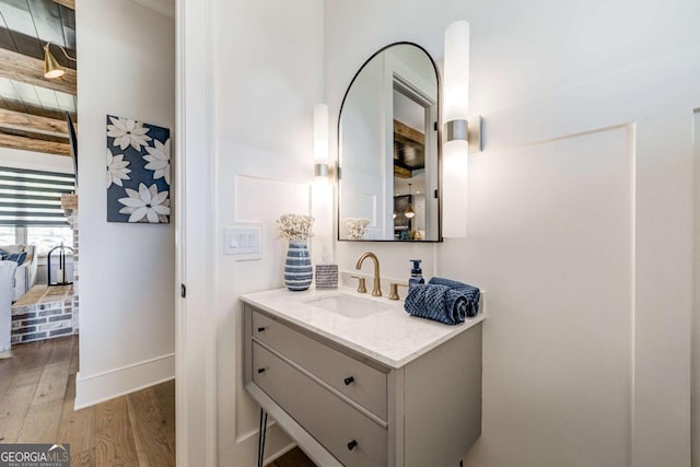 bathroom featuring beam ceiling, wood finished floors, and vanity