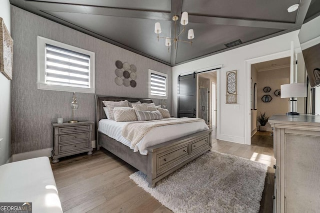 bedroom with a barn door, light wood-style flooring, baseboards, wallpapered walls, and crown molding