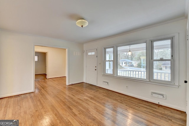 entryway with ornamental molding, light wood-type flooring, visible vents, and baseboards