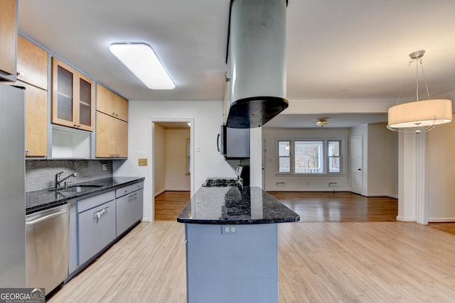 kitchen featuring dark stone counters, appliances with stainless steel finishes, glass insert cabinets, decorative light fixtures, and a sink