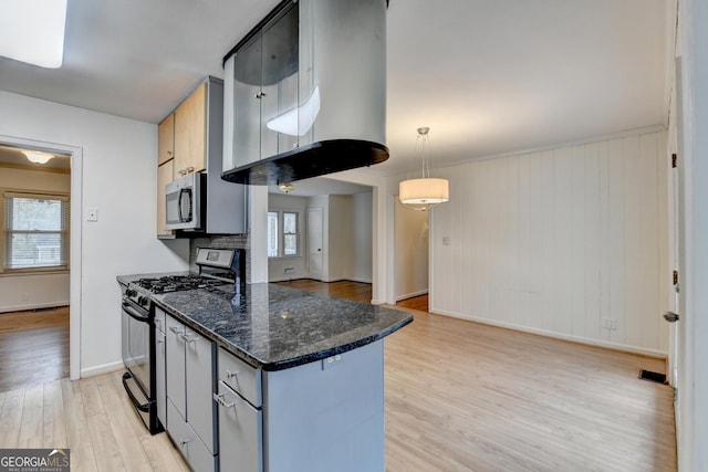 kitchen with black gas range, baseboards, light wood finished floors, stainless steel microwave, and pendant lighting