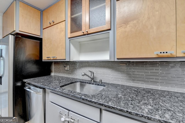 kitchen featuring a sink, appliances with stainless steel finishes, decorative backsplash, dark stone counters, and glass insert cabinets