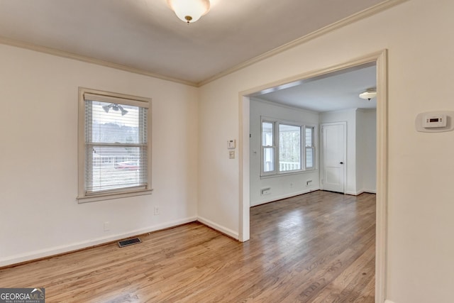 interior space with light wood-type flooring, baseboards, visible vents, and crown molding