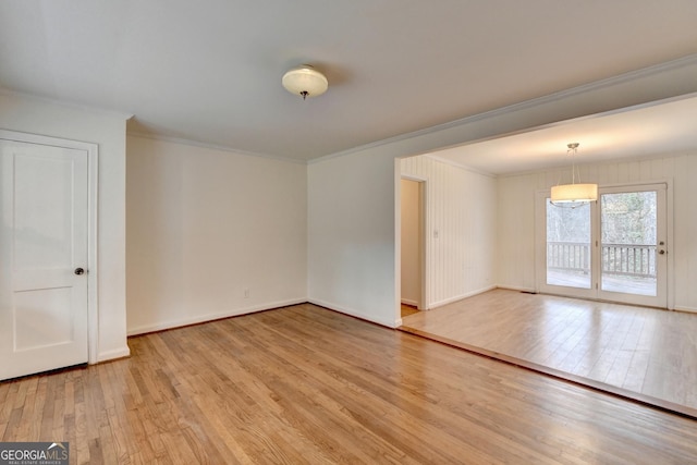 empty room featuring baseboards, crown molding, and light wood finished floors