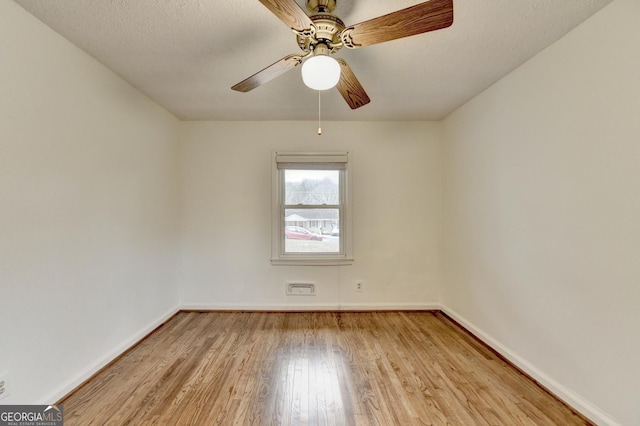 spare room featuring light wood-type flooring, ceiling fan, a textured ceiling, and baseboards