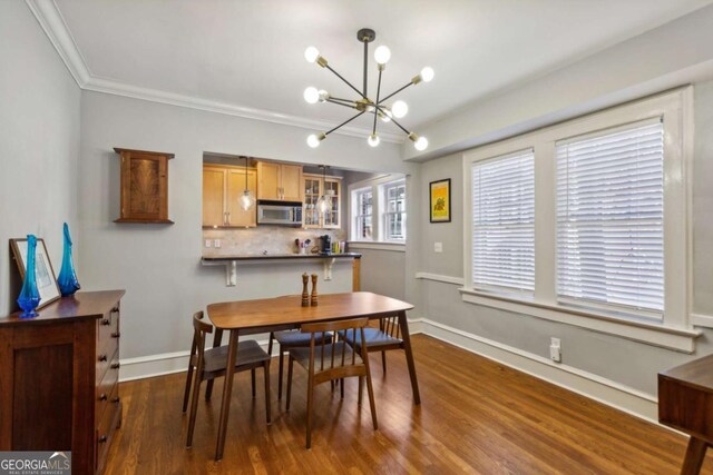 dining room featuring dark wood-style floors, crown molding, baseboards, and an inviting chandelier