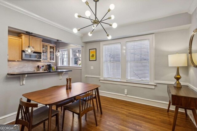 dining room with dark wood-style floors, a chandelier, crown molding, and baseboards