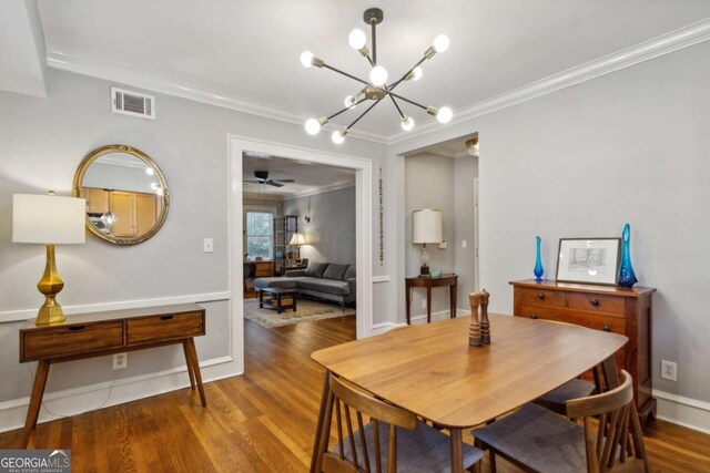 dining room with a chandelier, wood finished floors, visible vents, baseboards, and ornamental molding