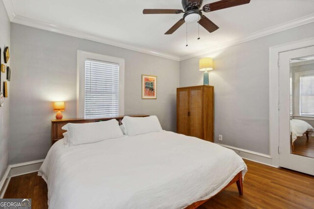 bedroom featuring dark wood-type flooring, crown molding, baseboards, and ceiling fan