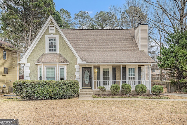 view of front of property with a porch, roof with shingles, a chimney, and a front lawn