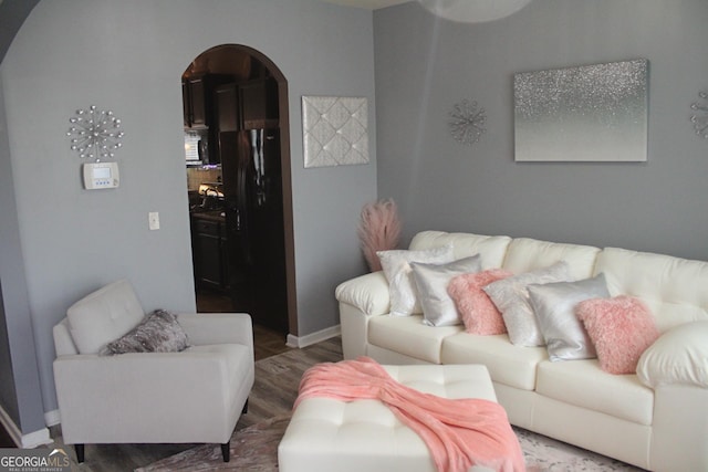 living area with arched walkways, dark wood finished floors, and baseboards