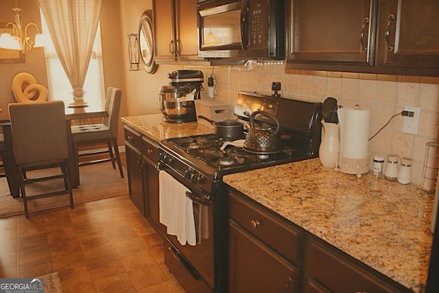 kitchen featuring light stone countertops, black appliances, dark brown cabinetry, and backsplash