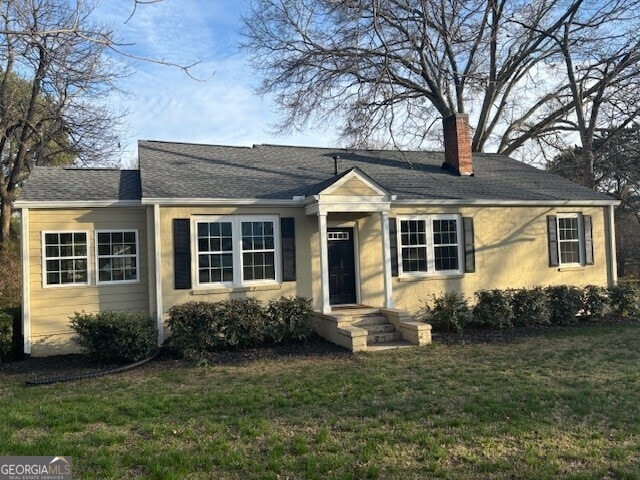 ranch-style house featuring a chimney and a front lawn