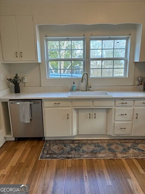 kitchen featuring a sink, white cabinets, light countertops, and stainless steel dishwasher