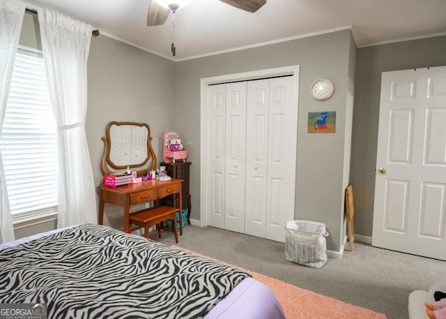 carpeted bedroom with a ceiling fan, a closet, baseboards, and crown molding