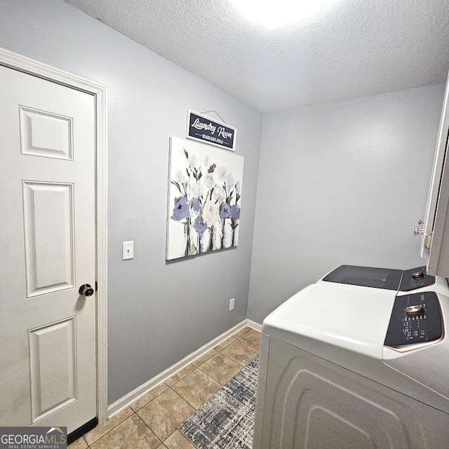 clothes washing area featuring a textured ceiling, light tile patterned flooring, baseboards, washer and dryer, and cabinet space