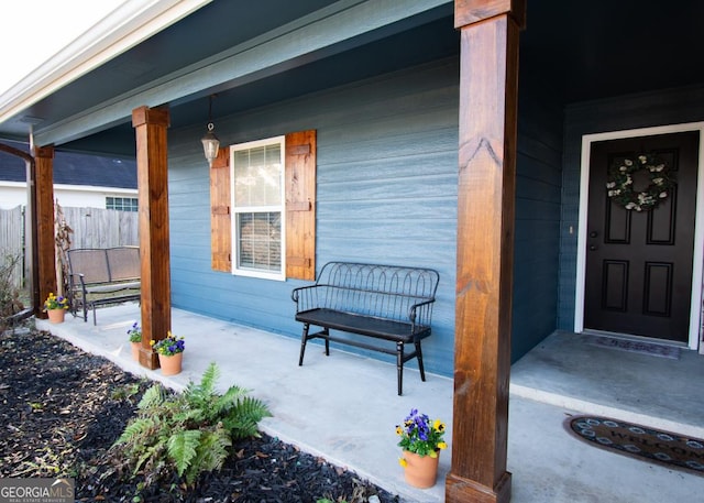 view of exterior entry with a porch and fence