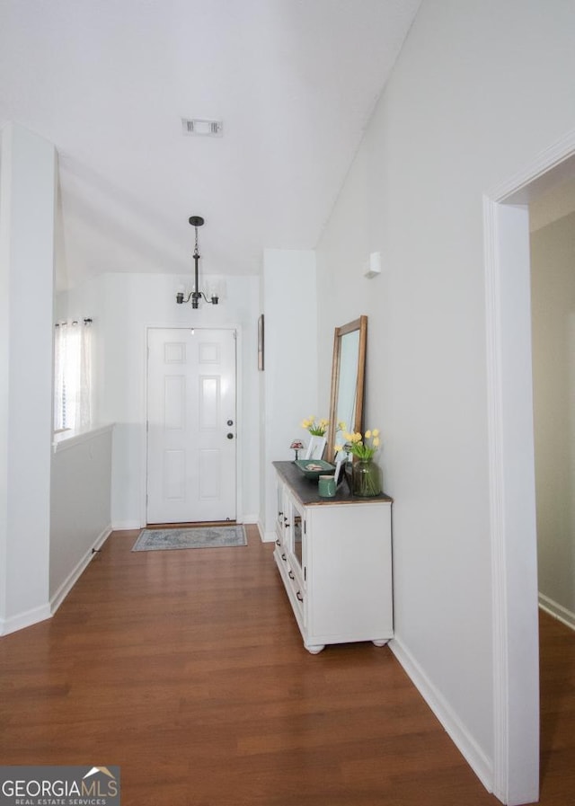 entrance foyer featuring dark wood-style floors, visible vents, a notable chandelier, and baseboards