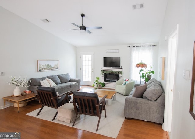 living area featuring a ceiling fan, visible vents, a fireplace, and light wood-style flooring