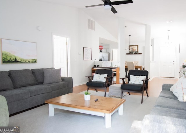 living room with a ceiling fan, visible vents, high vaulted ceiling, and baseboards