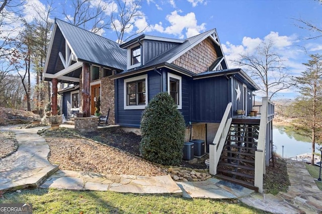 view of side of home featuring a water view, stairway, and metal roof