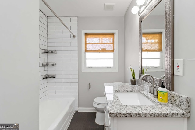 bathroom featuring toilet, visible vents, bathing tub / shower combination, vanity, and baseboards