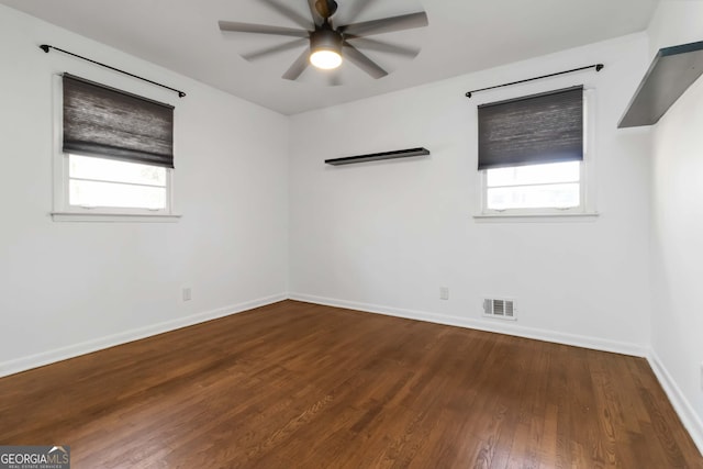 empty room with ceiling fan, visible vents, baseboards, and wood finished floors