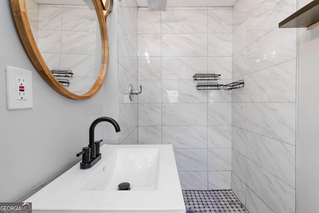 full bath featuring a tile shower and a sink