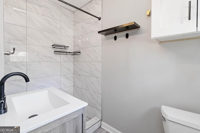 bathroom with tiled shower, a sink, and toilet