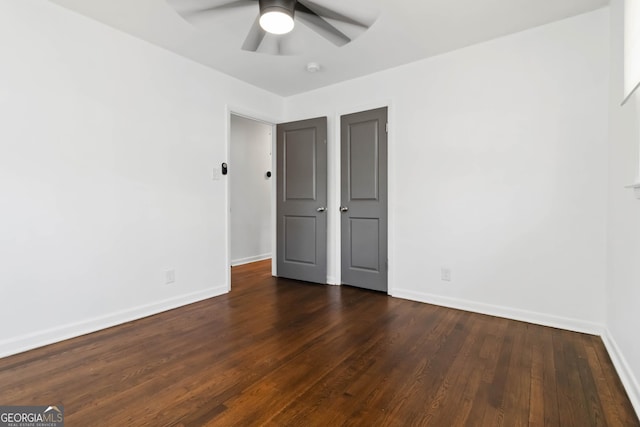 unfurnished bedroom featuring dark wood finished floors, baseboards, and ceiling fan