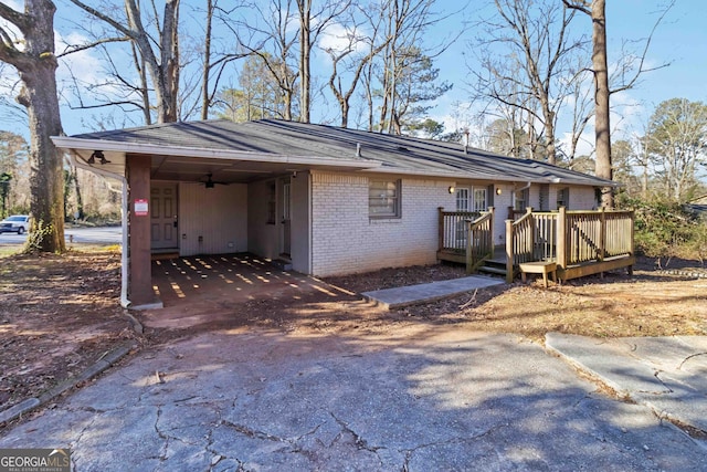 view of front of home featuring a wooden deck, aphalt driveway, a carport, and brick siding