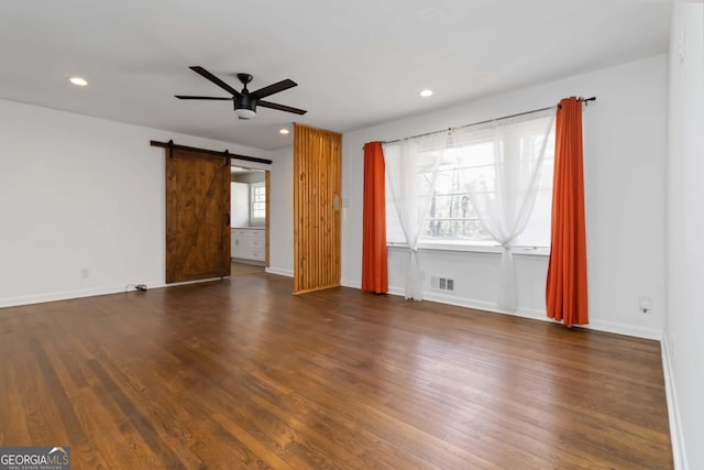 unfurnished living room featuring dark wood-style floors, a barn door, a ceiling fan, and recessed lighting