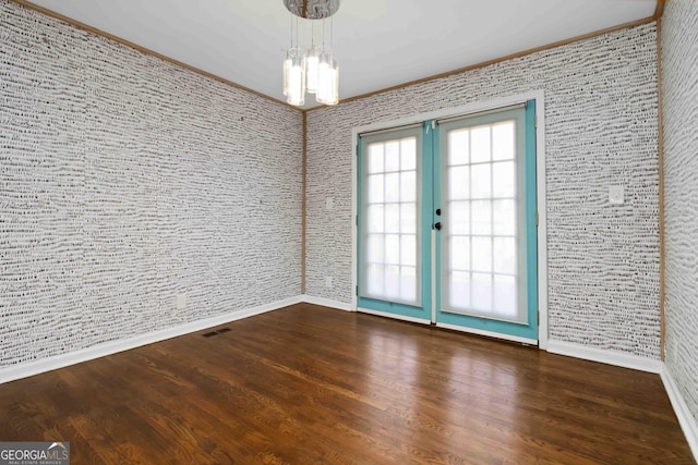 unfurnished room featuring dark wood-style floors, baseboards, visible vents, and a notable chandelier