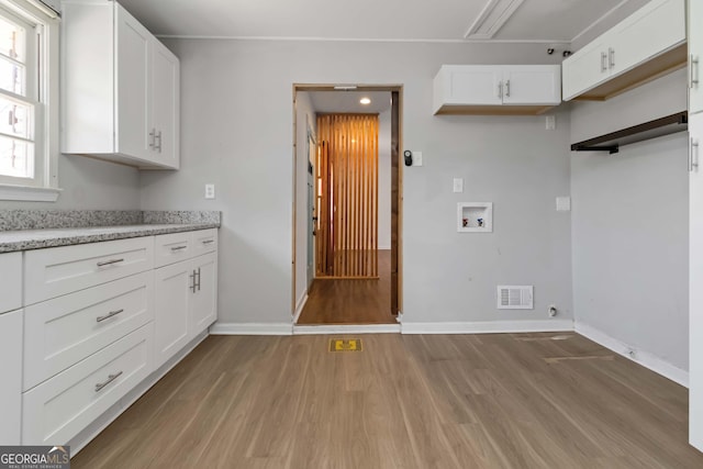 kitchen featuring light wood-type flooring, white cabinets, visible vents, and baseboards