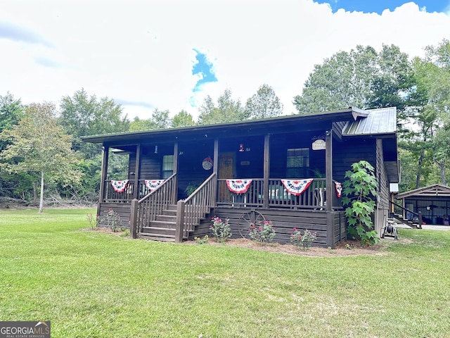 view of front of house with covered porch, metal roof, and a front lawn