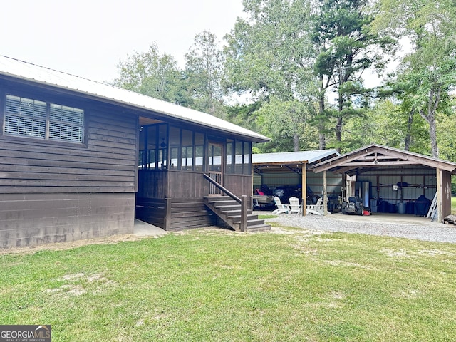 view of home's exterior featuring an outbuilding, metal roof, a lawn, and a detached carport