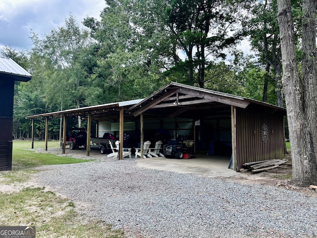 view of vehicle parking with a carport, an outbuilding, and gravel driveway