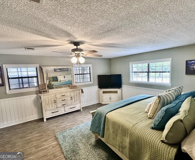 bedroom with wainscoting, visible vents, and multiple windows