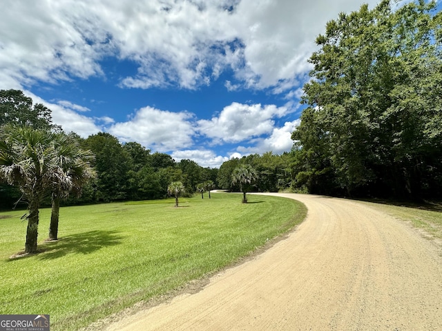 surrounding community with dirt driveway and a lawn