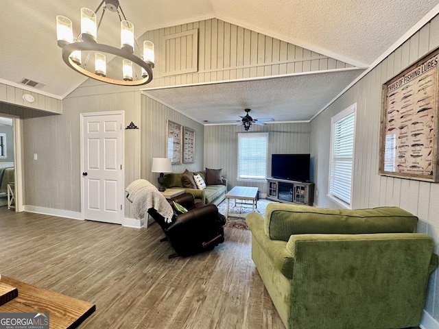 living area with a textured ceiling, visible vents, vaulted ceiling, and wood finished floors