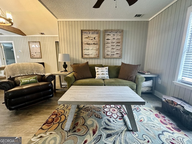 living area featuring ceiling fan, visible vents, wood finished floors, and ornamental molding