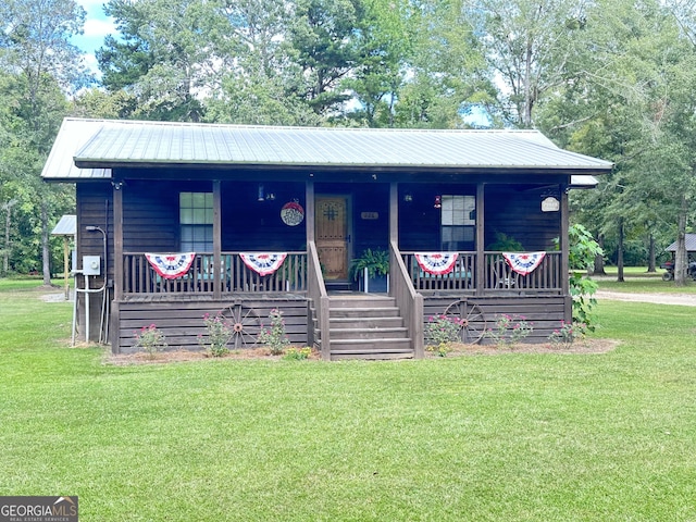 view of front of property featuring covered porch, metal roof, and a front lawn