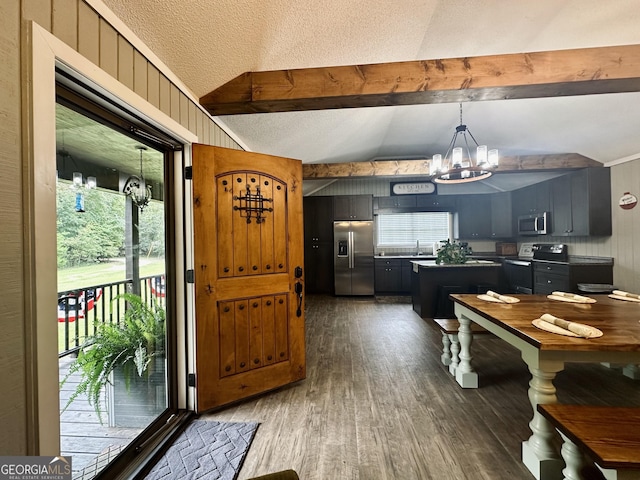 interior space with dark wood finished floors, vaulted ceiling with beams, a textured ceiling, a chandelier, and a wealth of natural light