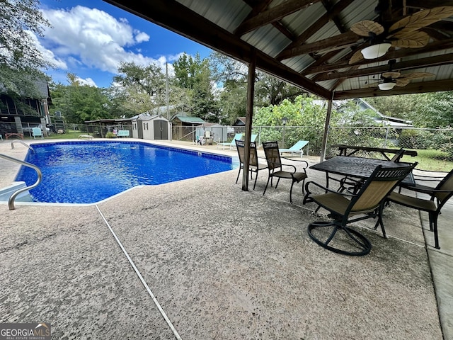 view of pool with an outbuilding, a patio area, ceiling fan, fence, and a shed