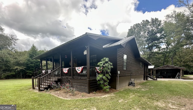 view of property exterior with a porch, stairway, metal roof, and a yard