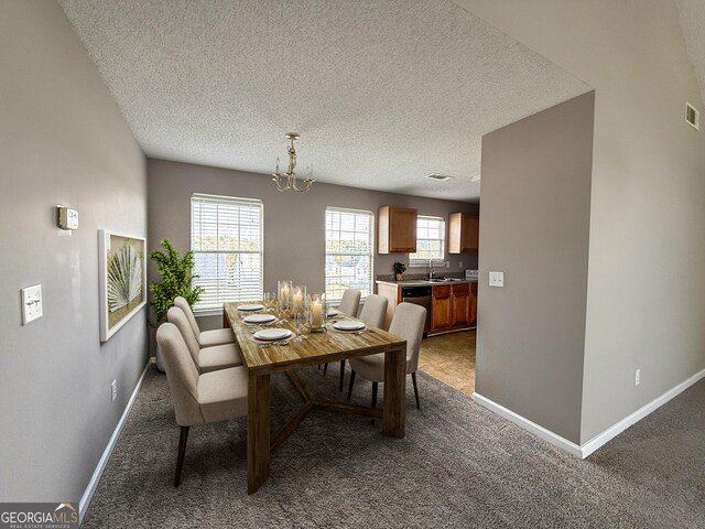 carpeted dining space featuring visible vents, a textured ceiling, baseboards, and a sink