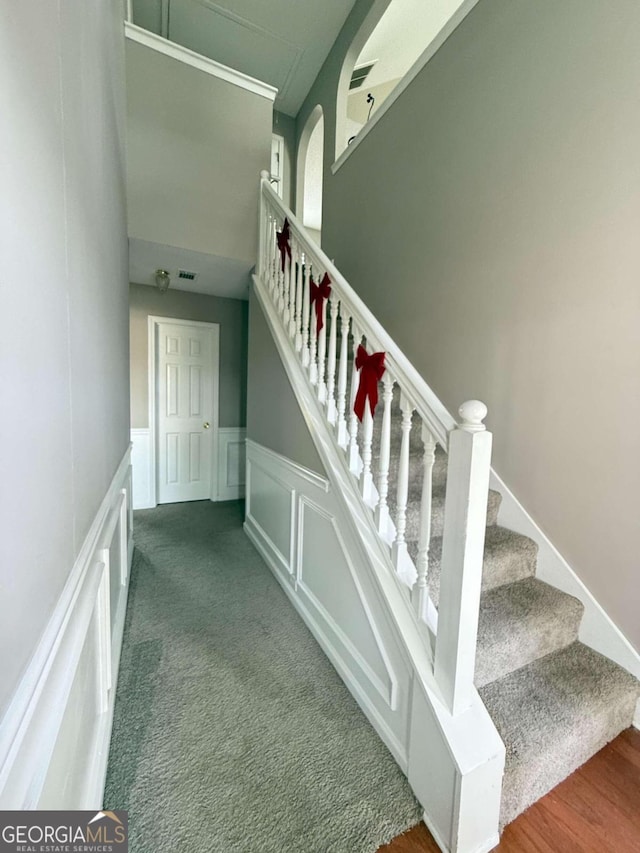 staircase with wainscoting, carpet flooring, visible vents, and a decorative wall