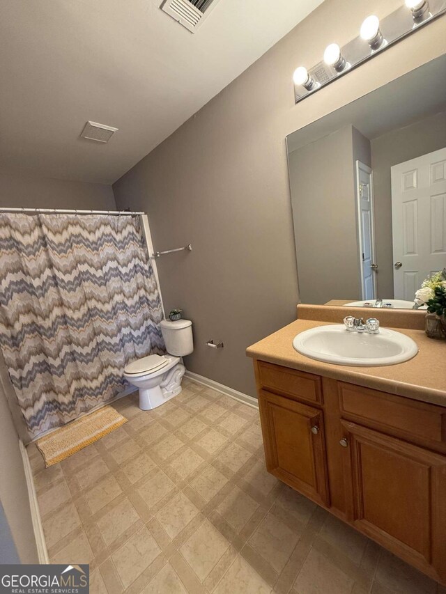 bathroom featuring baseboards, visible vents, toilet, tile patterned floors, and vanity