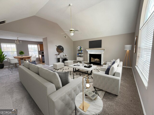 carpeted living room with a fireplace with raised hearth, ceiling fan with notable chandelier, visible vents, and baseboards