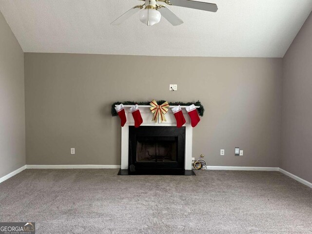 unfurnished living room featuring a fireplace with flush hearth, carpet flooring, vaulted ceiling, and ceiling fan